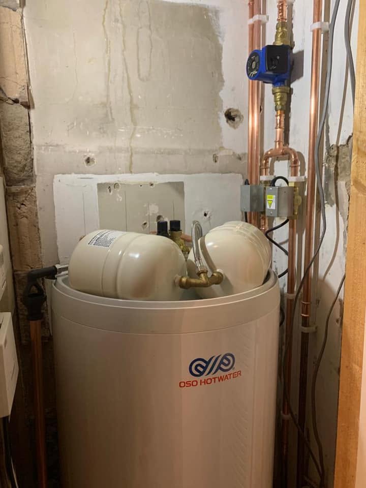 An unvented hot water cylinder with its expansion vessels and copper pipework, fitted in a cupboard